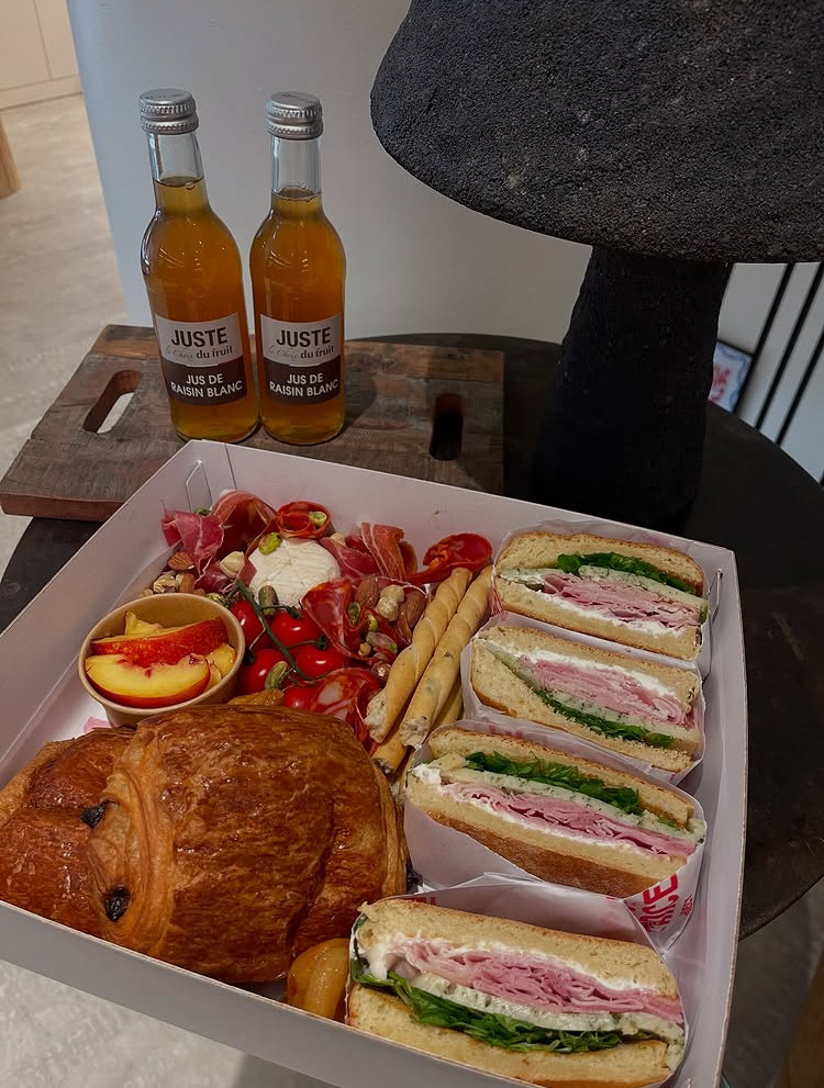Plateau repas type brunch avec sandwichs et pains au chocolat avec bouteilles de jus de raisin